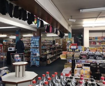 Inside a petrol station shop with various items on sale and an empty display stand.
