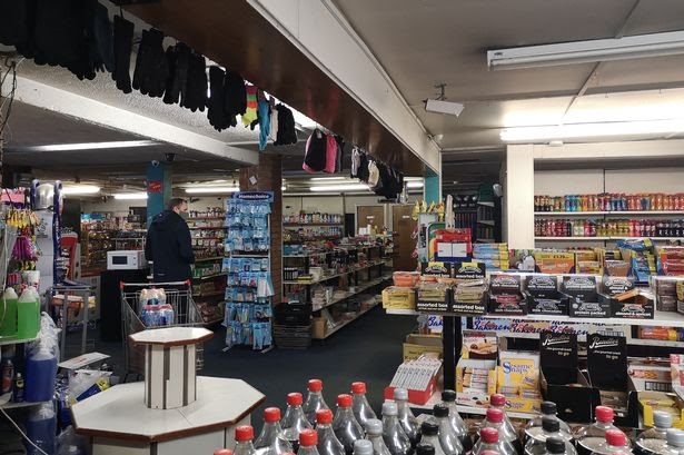 Inside a petrol station shop with various items on sale and an empty display stand.