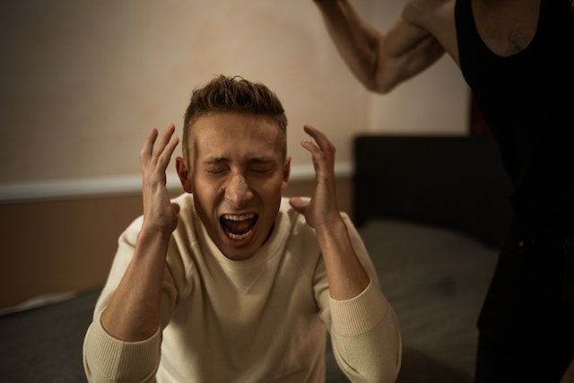 Man crying out with his hands held up close to his head.