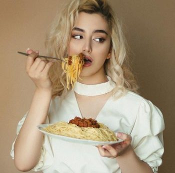 woman in white blouse eating spaghetti Bolognese