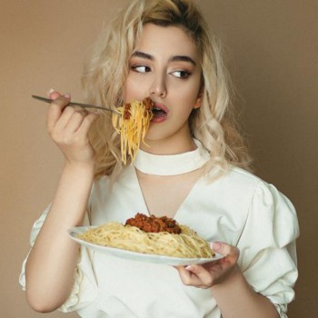 woman in white blouse eating spaghetti Bolognese