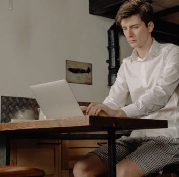 man in lounge wear sitting at a table using a.laptop