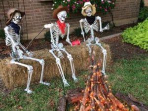 Three skeletons with cowboy hats sitting around an ornamental campfire
