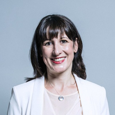 Rachel Reeves. A white woman with medium long dark hy. She is wearing a white jacket and light cream top with a small silver necklace.