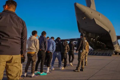Colombians in shackles being loaded on to a military transport plane. Military personnel looking on. No faces are shown