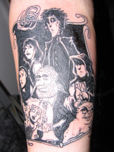 Arm tattooed with various characters from the Sandman graphic novels.