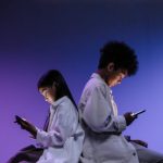 Kids Sitting Back to back Using Smartphones. Plain purple background fading to black at the top