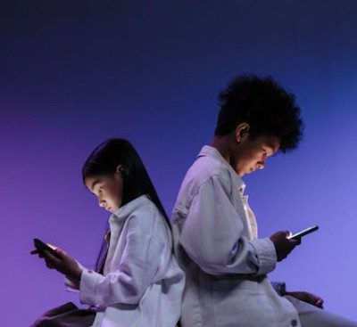 Kids Sitting Back to back Using Smartphones. Plain purple background fading to black at the top
