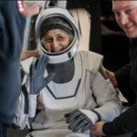 Astronaut Suni Williams in white space suit waving at the camera