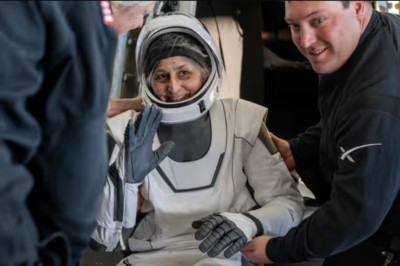 Astronaut Suni Williams in white space suit waving at the camera