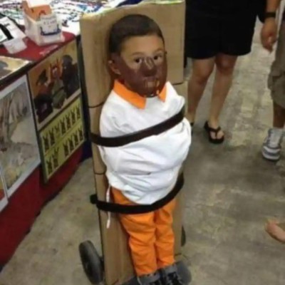 A child tied to a sack truck with a hockey mask looking like Hannibal Lecter