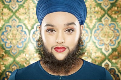 A young adult lady with a beard wearing a blue turban and blue smock top.