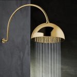 A shower head finished in gold with water streaming out