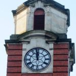 A classic large clock with ornamental hands pointing to Roman numerals on the roof of Swansea railway station.