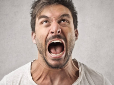Man in a white tee shirt shouting and looking angry