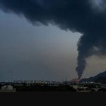 Distant view of black smoke rising from a building - the Qeshm desalination facility in Iran.