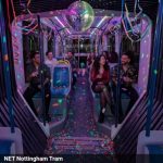 Inside of a tram with disco lights and a mirror ball hanging from the ceiling.