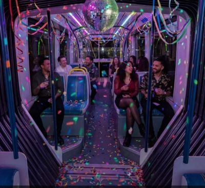Inside of a tram with disco lights and a mirror ball hanging from the ceiling.