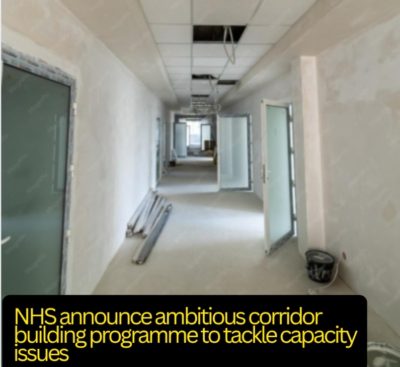A long corridor with plastered walls and a few ceiling panels missing. Various building materials and buckets on the floor. Text - NHS announce ambitious corridor building programme to tackle capacity issues.